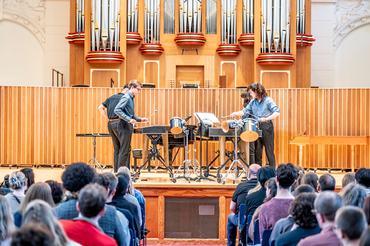 Students playing on the marimbas on a stage, with an audience watching them.